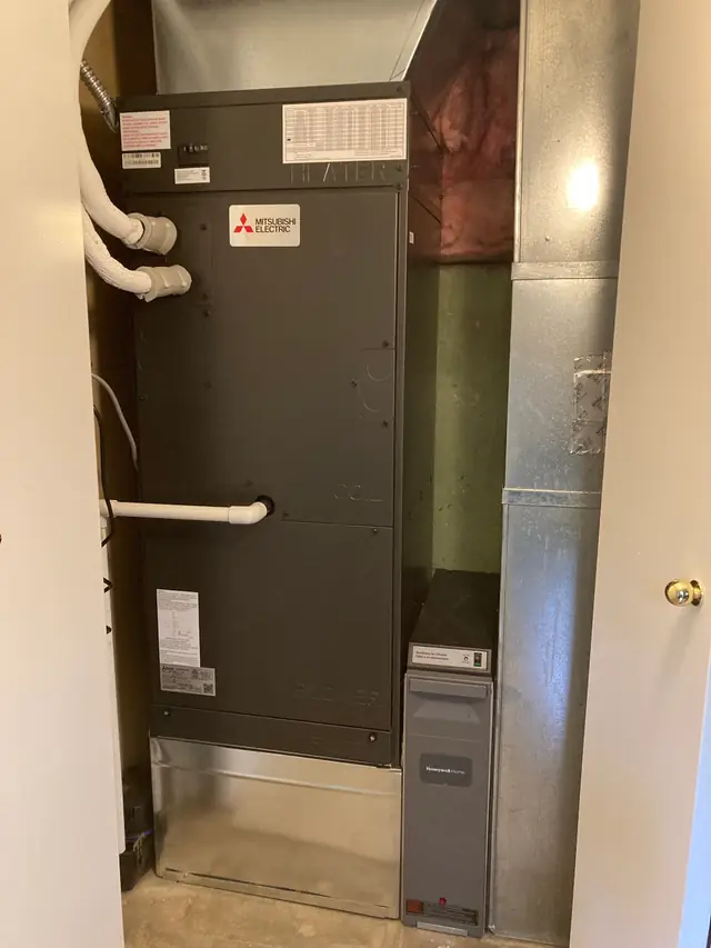 A ducted air handler installed in a utility closet with condensate piping