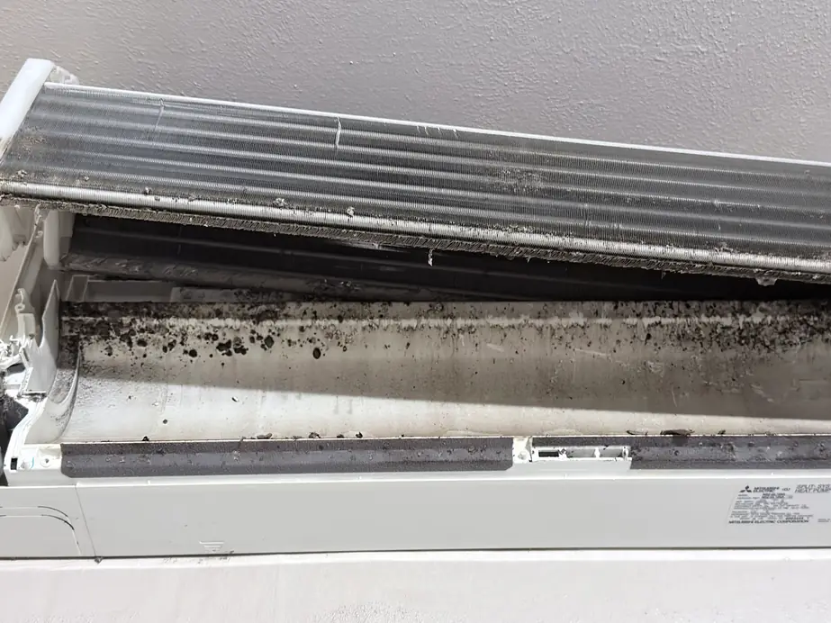 An indoor mini-split unit opened up to show a dirty coil and blower before cleaning