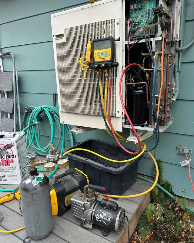 Manifold gauges, hoses and a vacuum pump hooked up to an outdoor unit during a service call