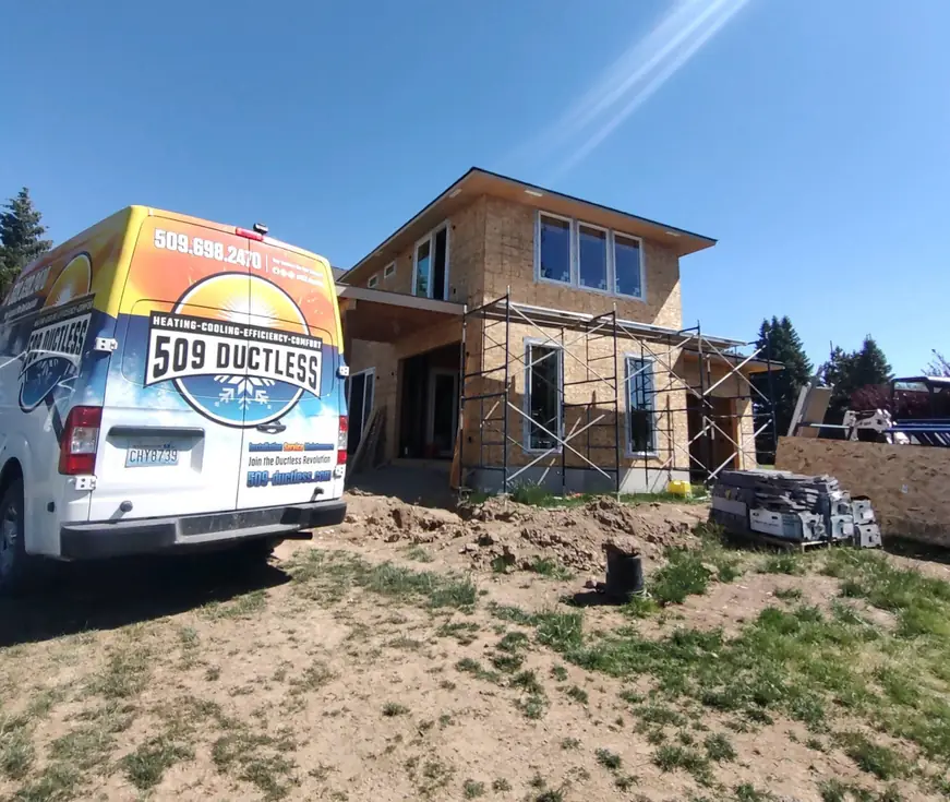 The wrapped 509 Ductless van parked at a new-construction house with scaffolding and a dirt lot